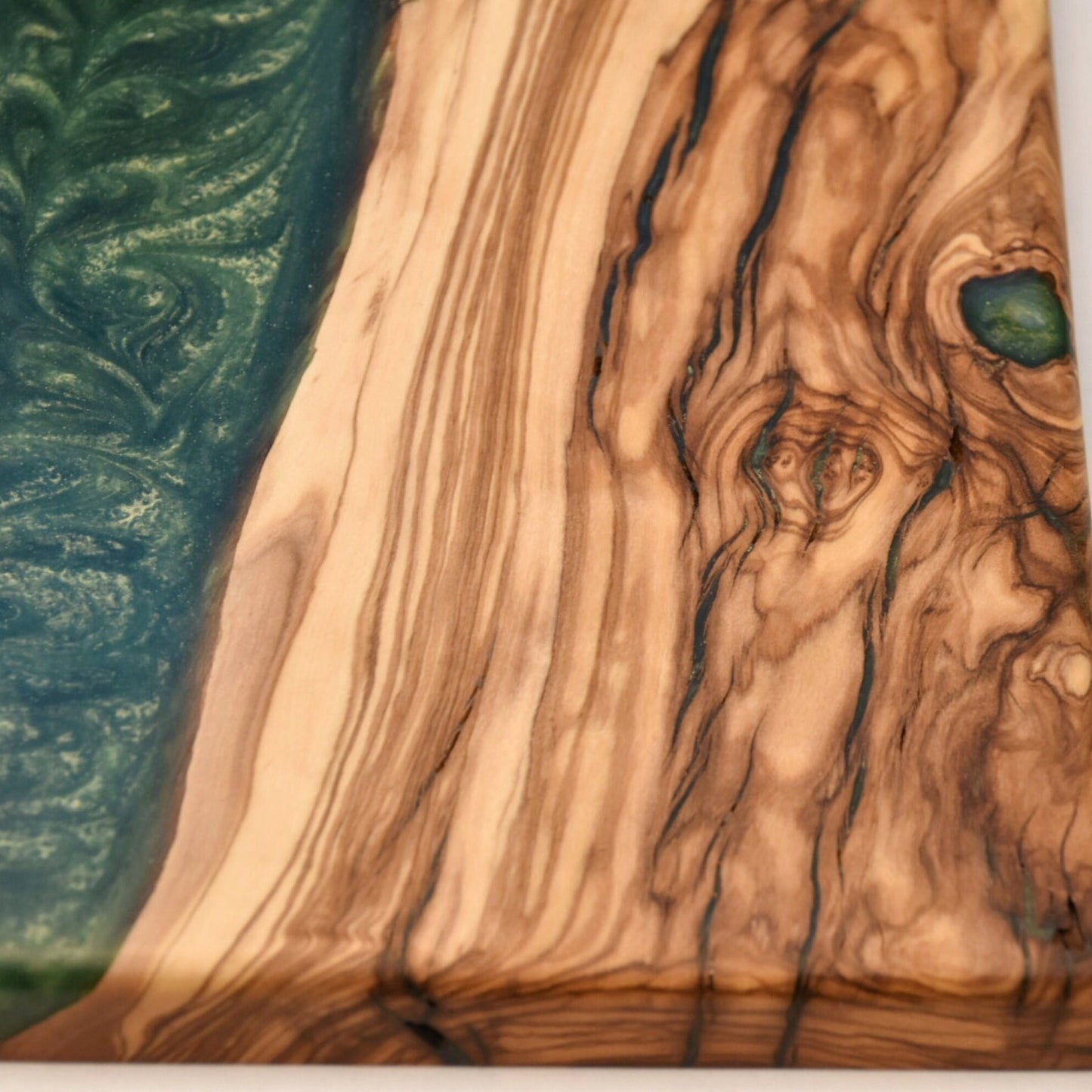 Detalle de veta natural de madera de olivo con resina epoxi verde