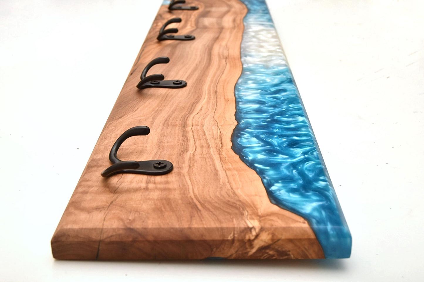 Perspectiva lateral de perchero con ganchos negros y diseño único en madera y epoxy