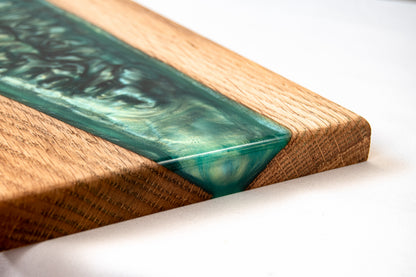Primer plano de la esquina de una tabla de roble con resina epoxy verde, sobre una superficie blanca