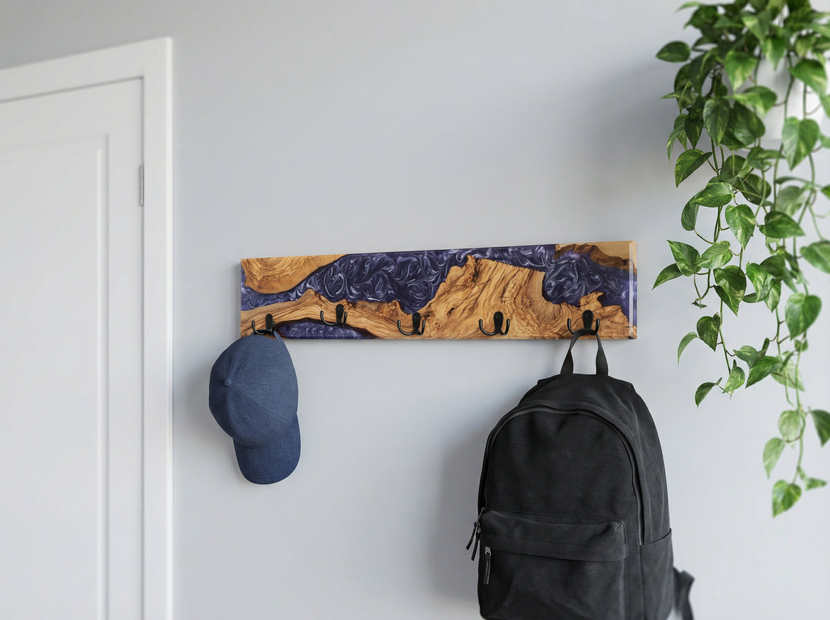 Perchero de pared en madera de olivo con resina violeta, gorro y mochila colgados, junto a planta
