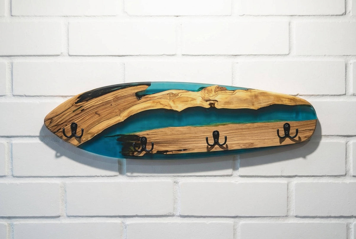 Perchero de pared en forma de skateboard, madera de olivo con resina epoxi azul, sobre pared de ladrillo blanco