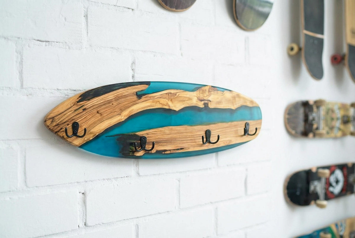 Perchero skate de madera de olivo y resina azul junto a una tabla de skateboard decorativa
