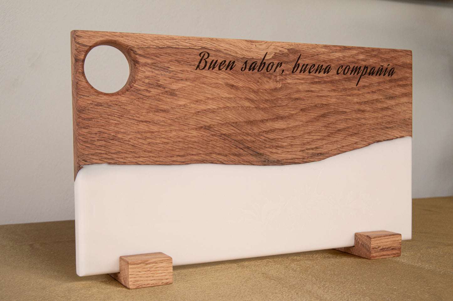 Tabla de madera de roble y resina epoxi blanca personalizada con frase grabada, apoyada en soportes de madera