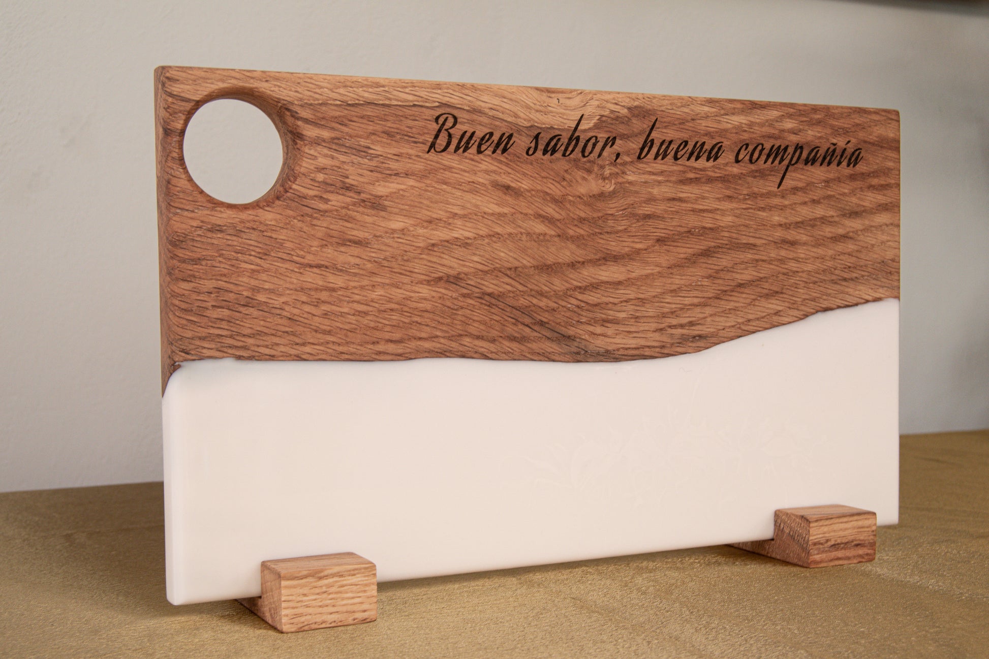 Tabla de madera de roble y resina epoxi blanca personalizada con frase grabada, apoyada en soportes de madera