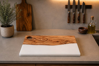Tabla de charcutería de madera de olivo con resina epoxi blanca sobre encimera de cocina