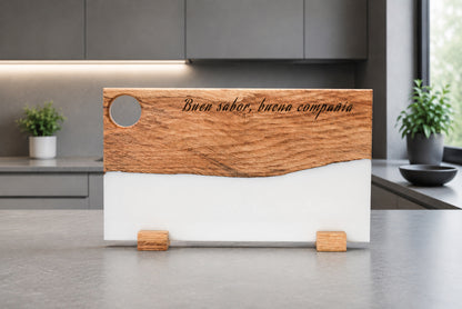 Tabla de madera de roble y resina epoxi blanca con grabado "Buen sabor, buena compañía" en cocina moderna gris con plantas