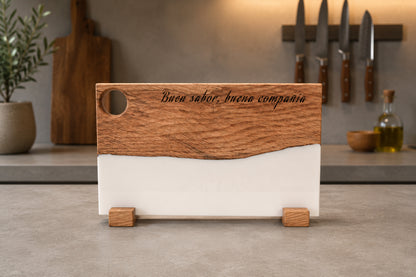 Tabla personalizada de roble y resina blanca con grabado "Buen sabor, buena compañía" en cocina moderna con cuchillos de pared