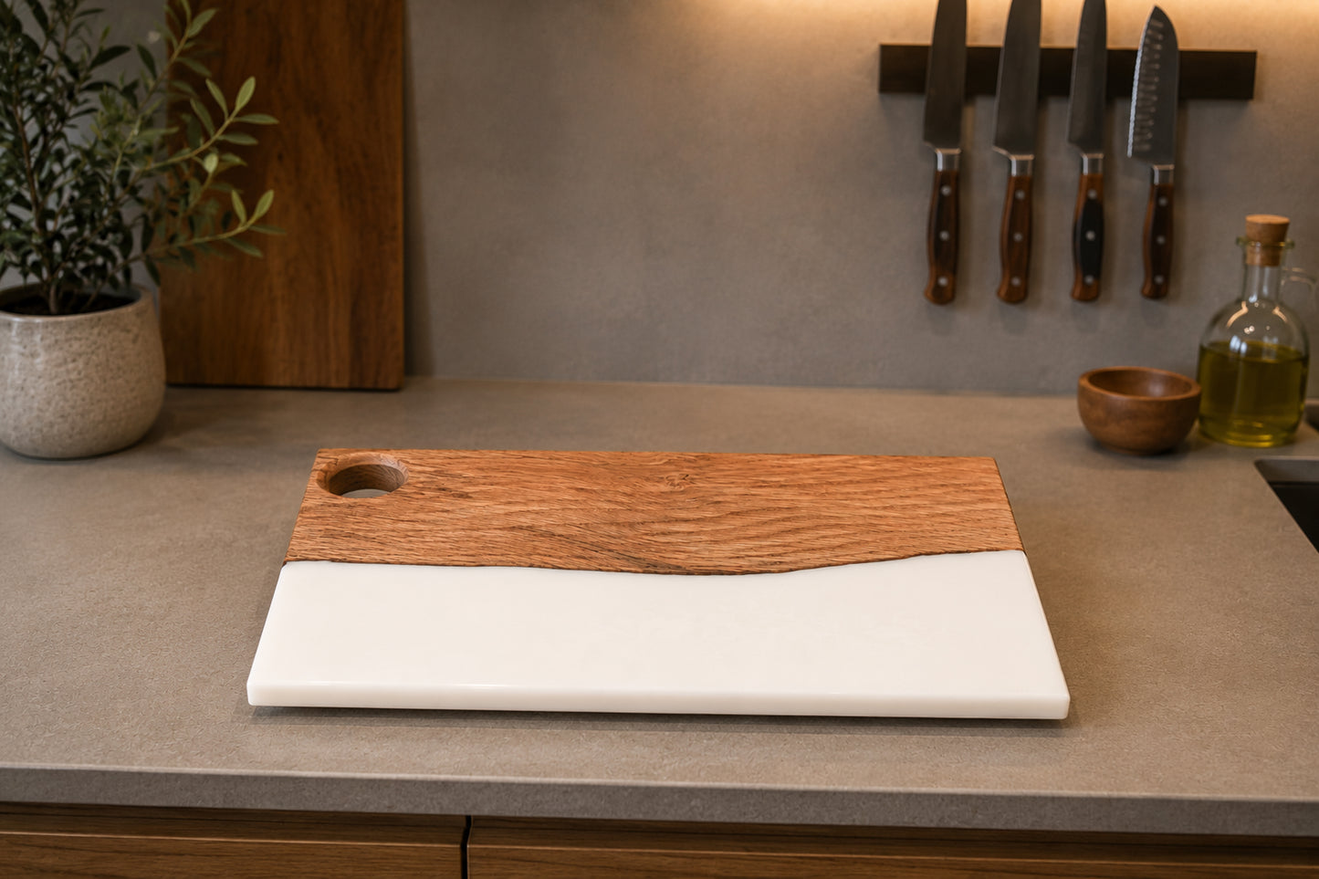 Tabla de madera de roble y resina epoxi blanca vacía sobre encimera de cocina con utensilios de fondo