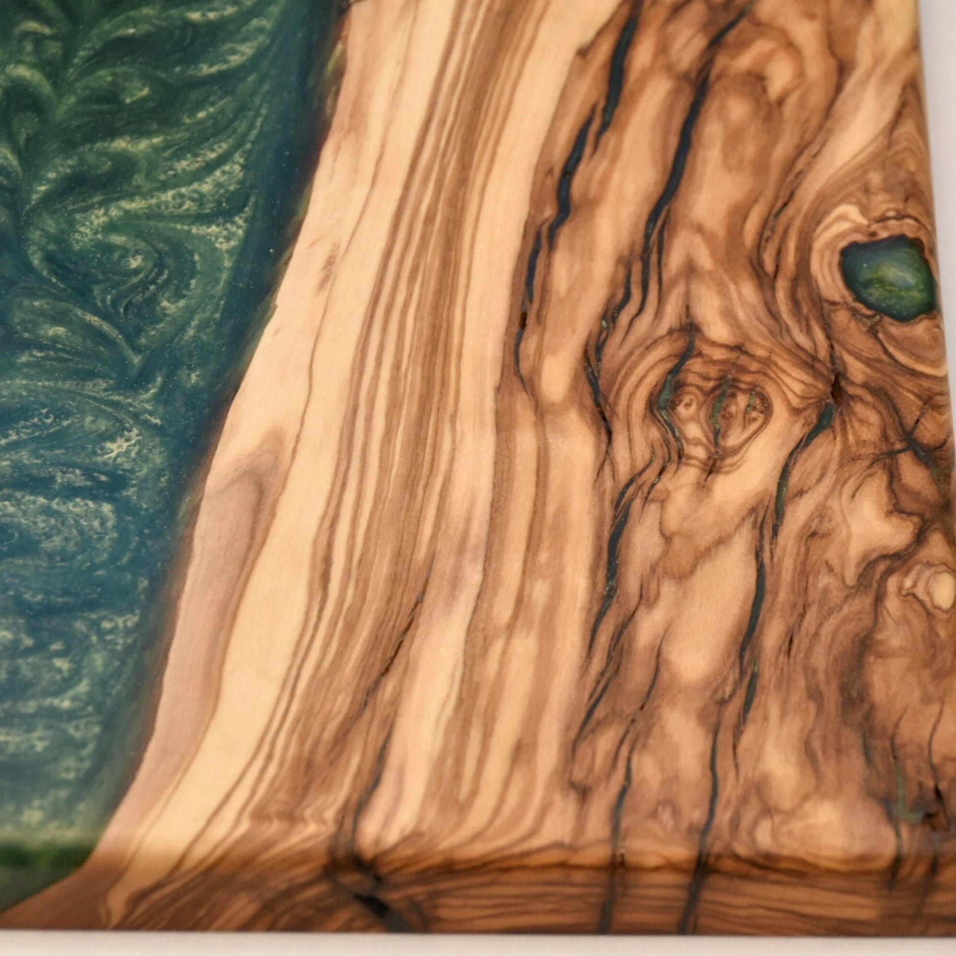 Detalle de veta natural de madera de olivo con resina epoxi verde