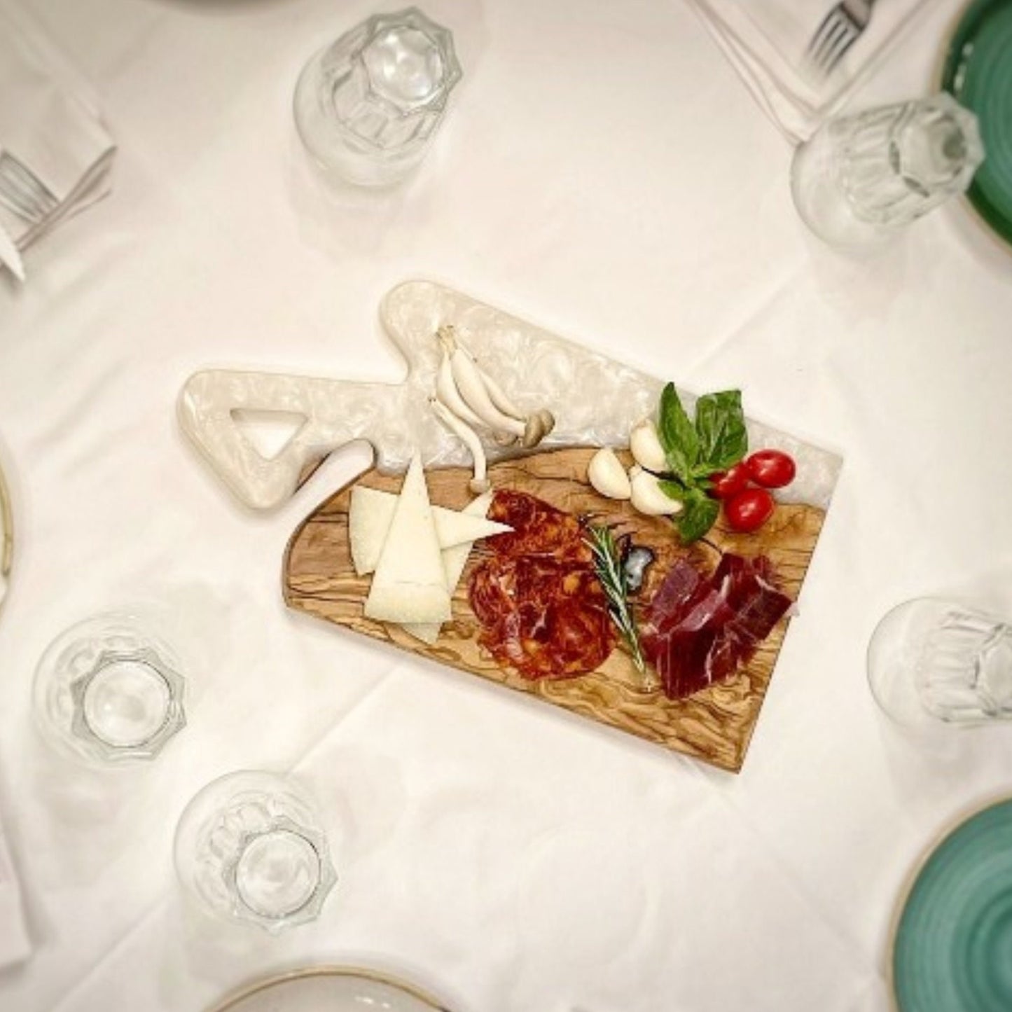 Tabla de embutidos con alimentos presentados sobre superficie de madera y resina