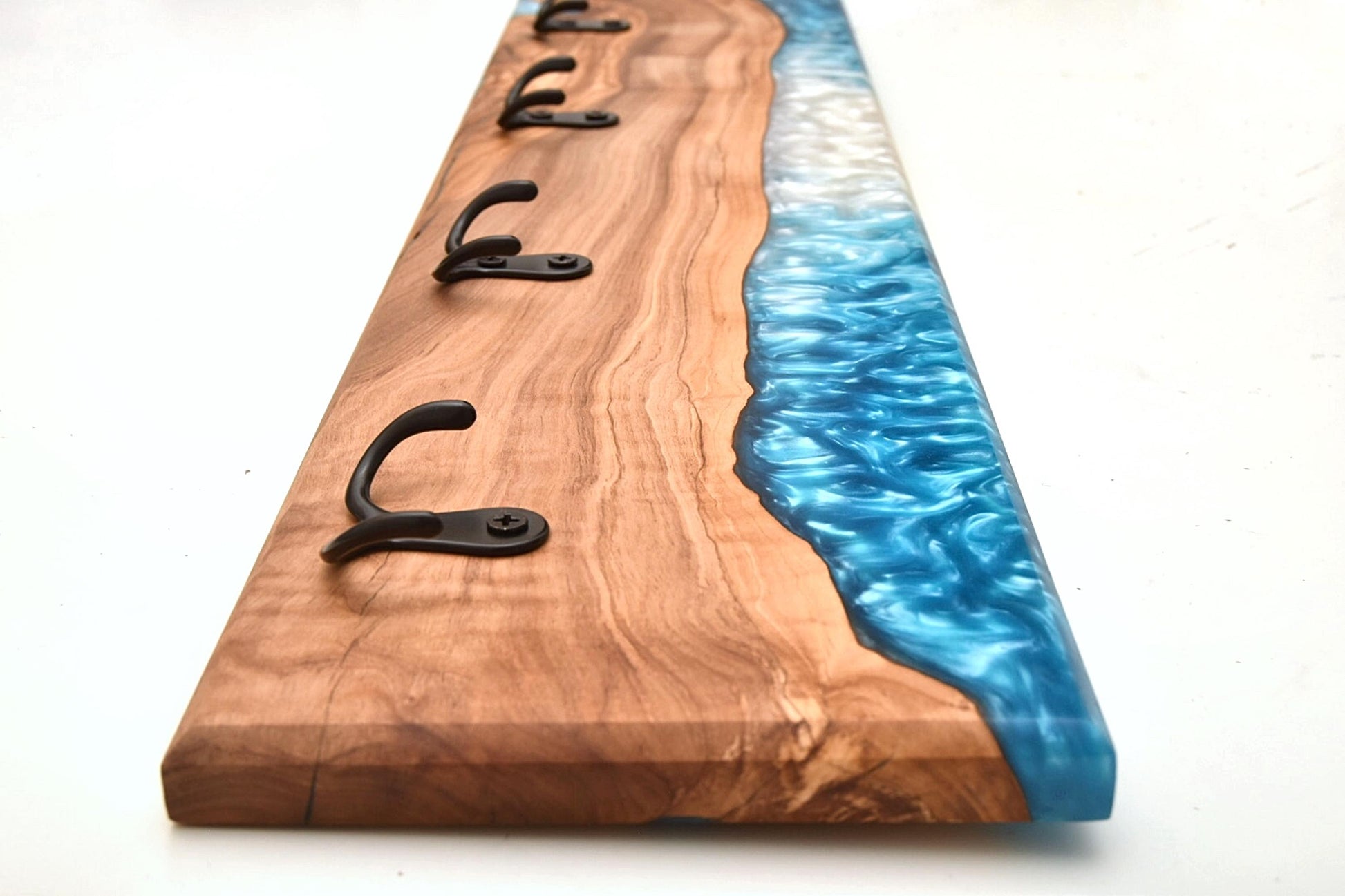 Perspectiva lateral de perchero con ganchos negros y diseño único en madera y epoxy