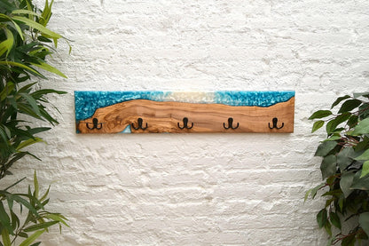 Perchero de madera y resina epoxy azul y blanco colgado en pared texturizada