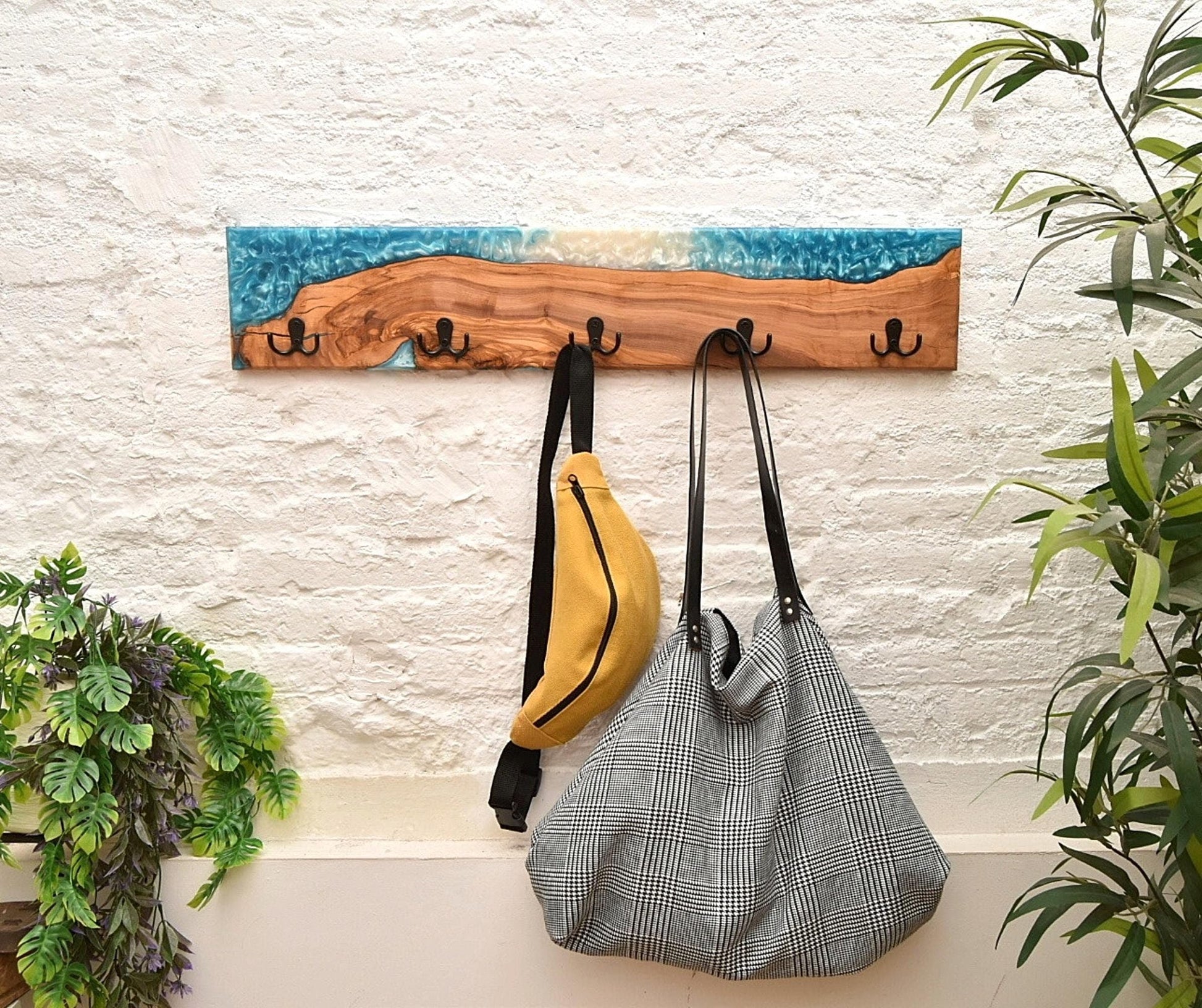 Perchero de madera y resina epoxy con bolsos y accesorios en ambiente decorativo