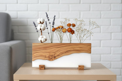 Portaplantas artesanal de madera de olivo y resina blanca con flores secas elegantes.