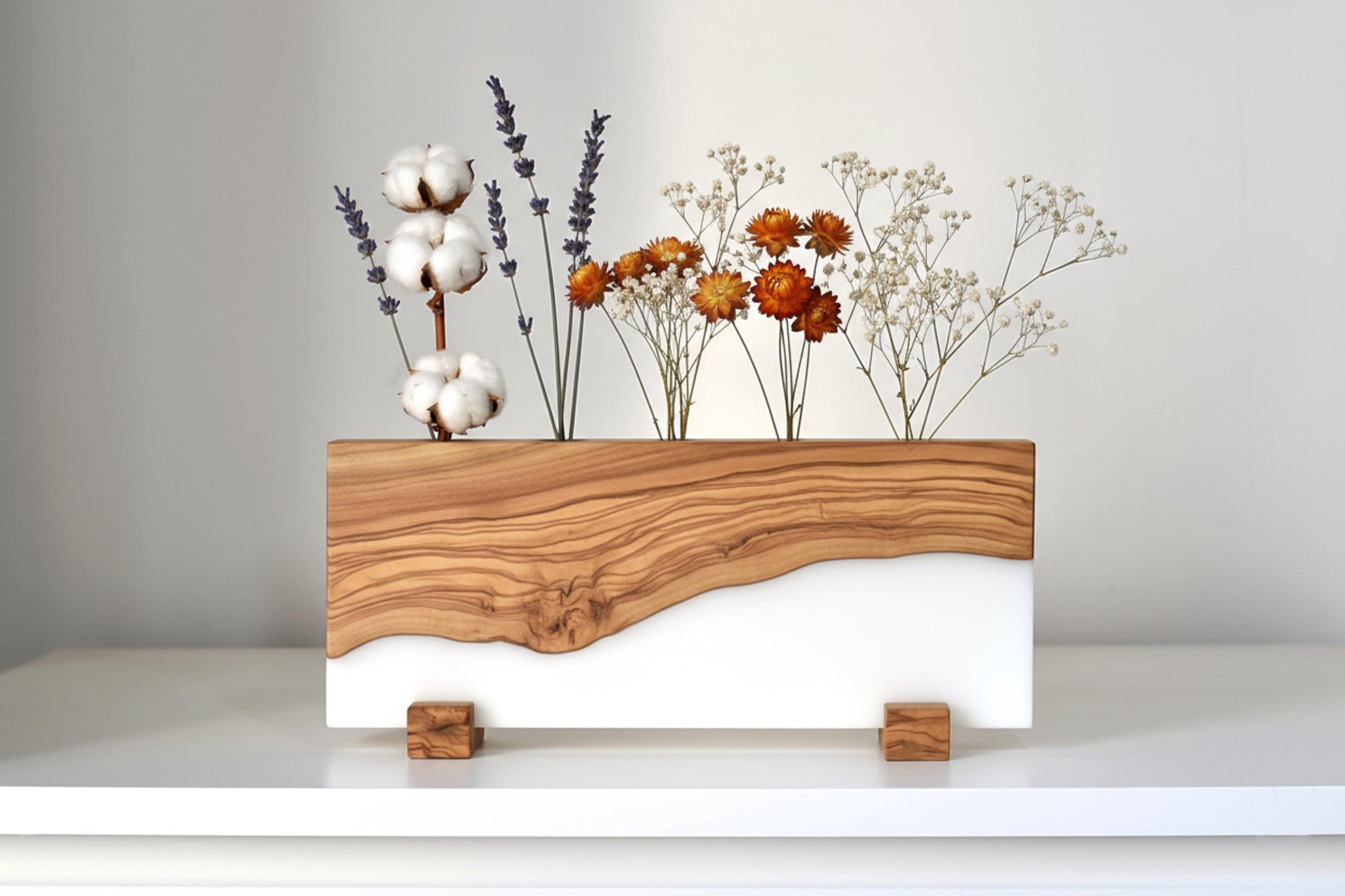 Portaplantas de madera de olivo y resina epoxi blanca con flores secas decorativas.