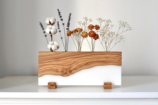Portaplantas de madera de olivo y resina epoxi blanca con flores secas decorativas.