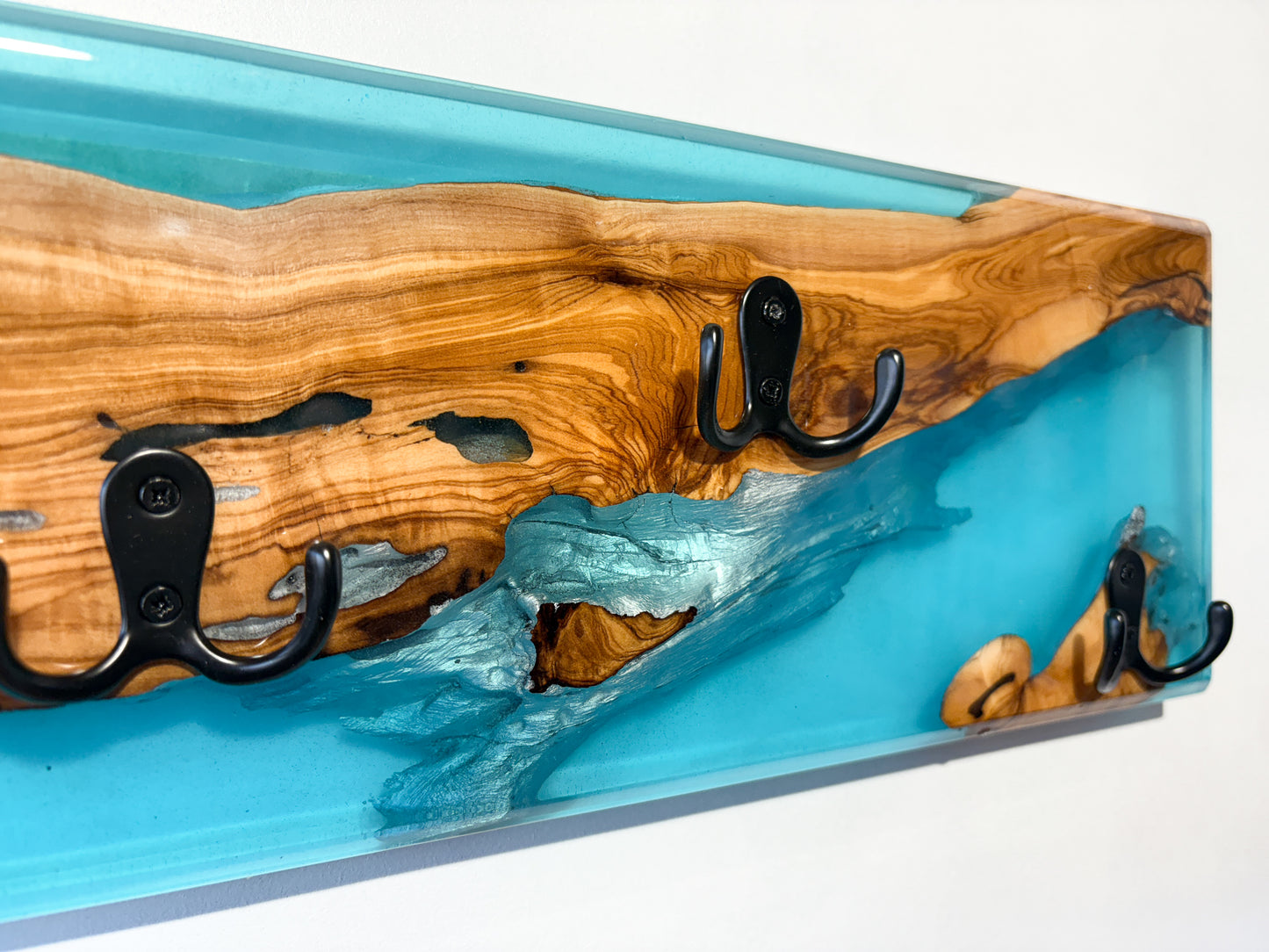 Detalle de madera de olivo con resina epoxy azul en perchero