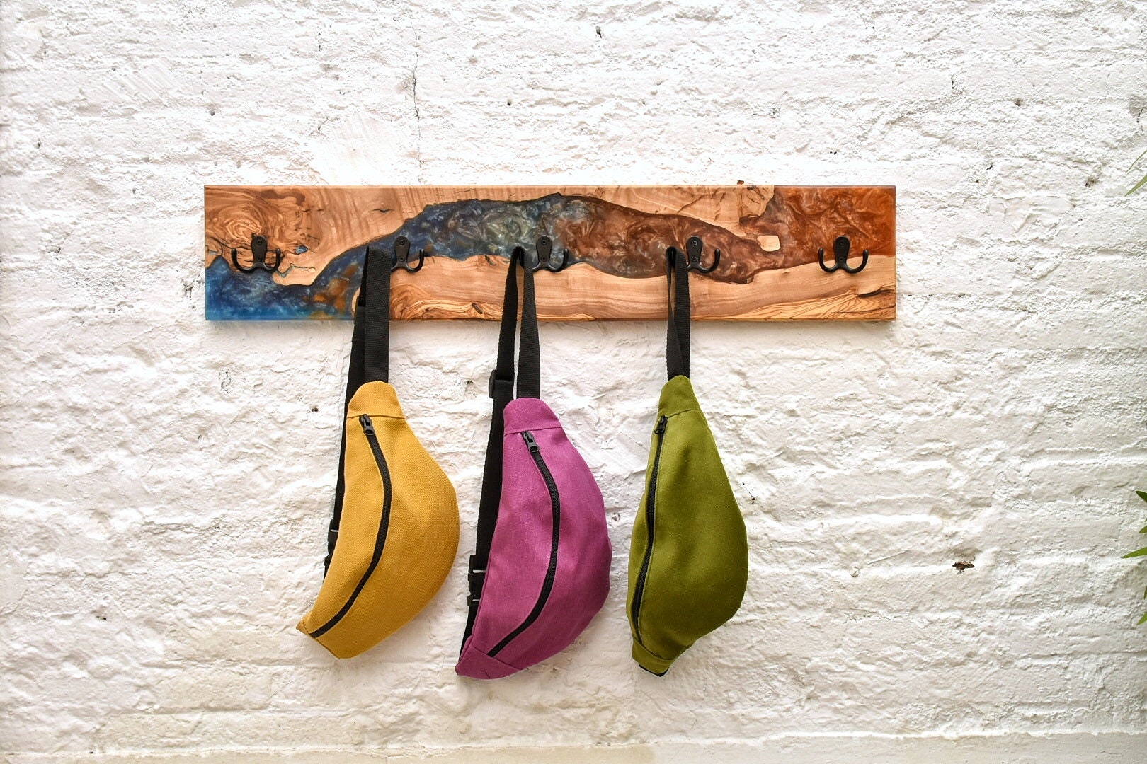 Perchero de pared en madera de olivo y resina Epoxi con bolsos colgados
