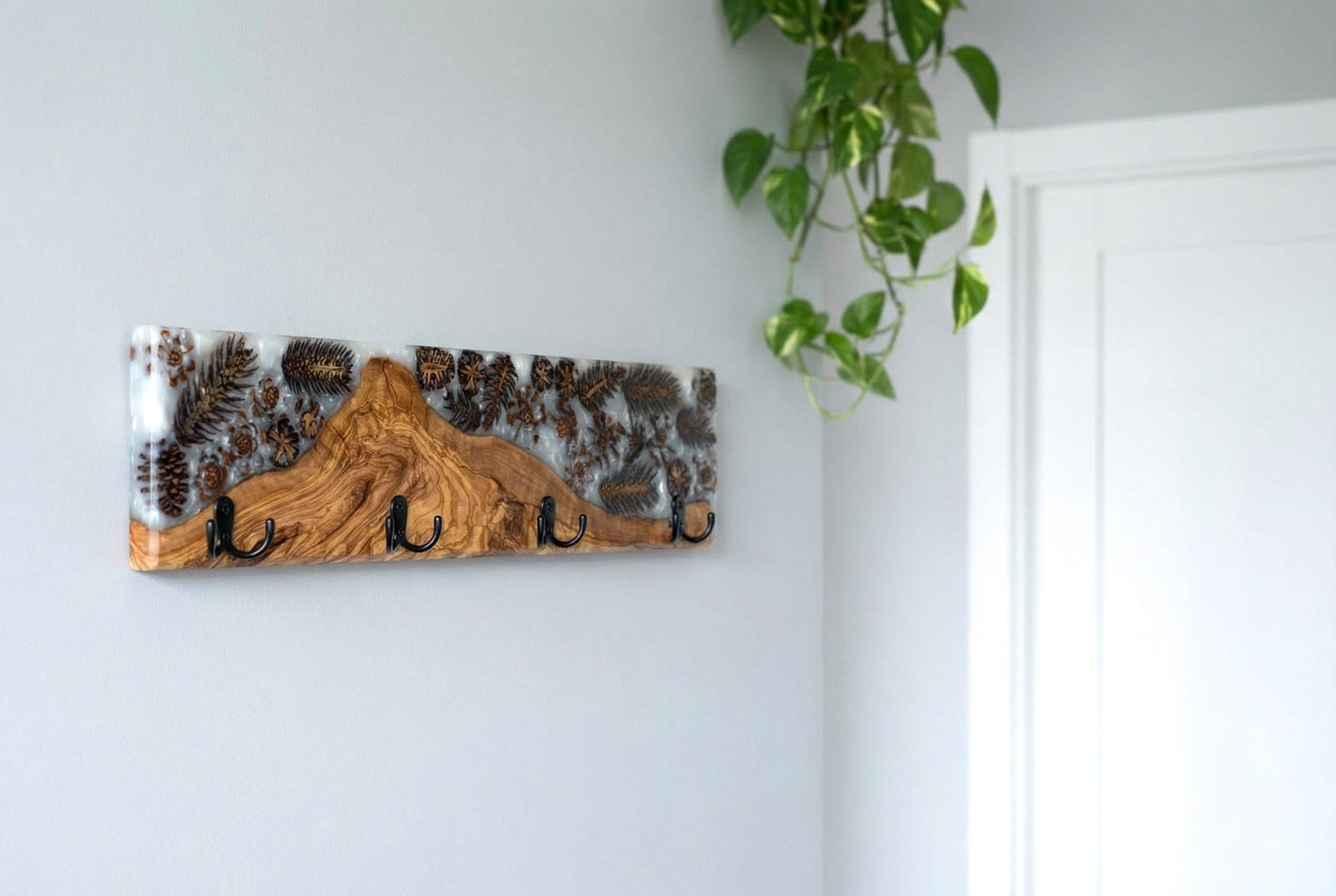 Perchero de pared en madera de olivo con resina epoxy y elementos naturales en ambiente decorativo