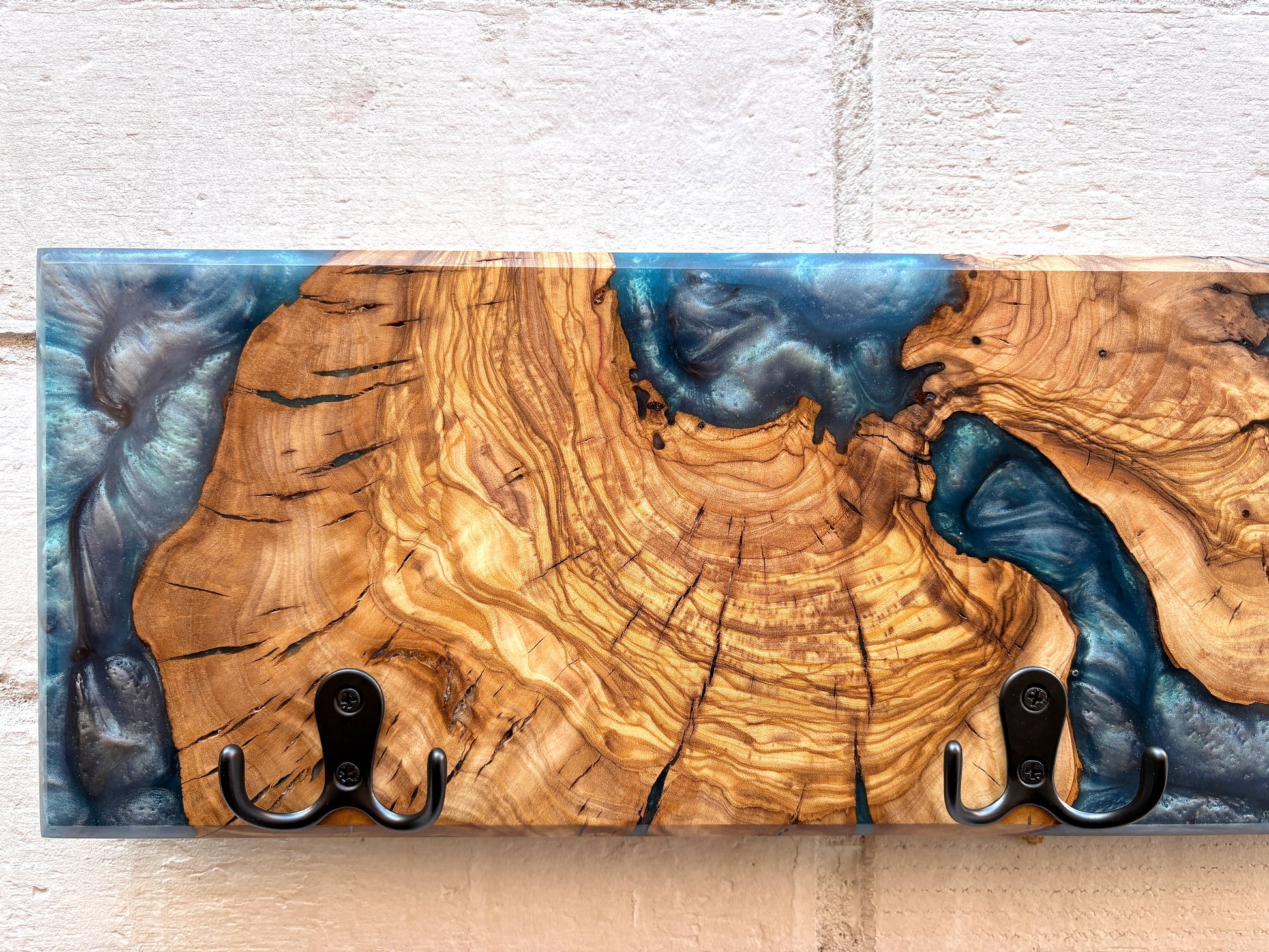 Detalle cercano de perchero en madera de olivo con resina epoxy azul