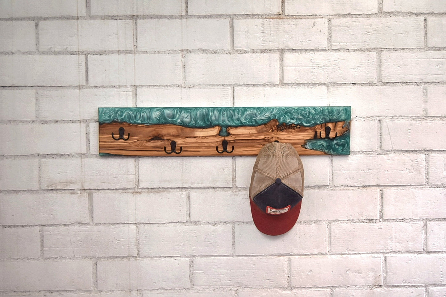 Perchero artesanal de olivo con resina epoxy verde en uso con gorra