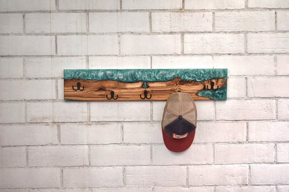 Perchero artesanal de olivo con resina epoxy verde en uso con gorra