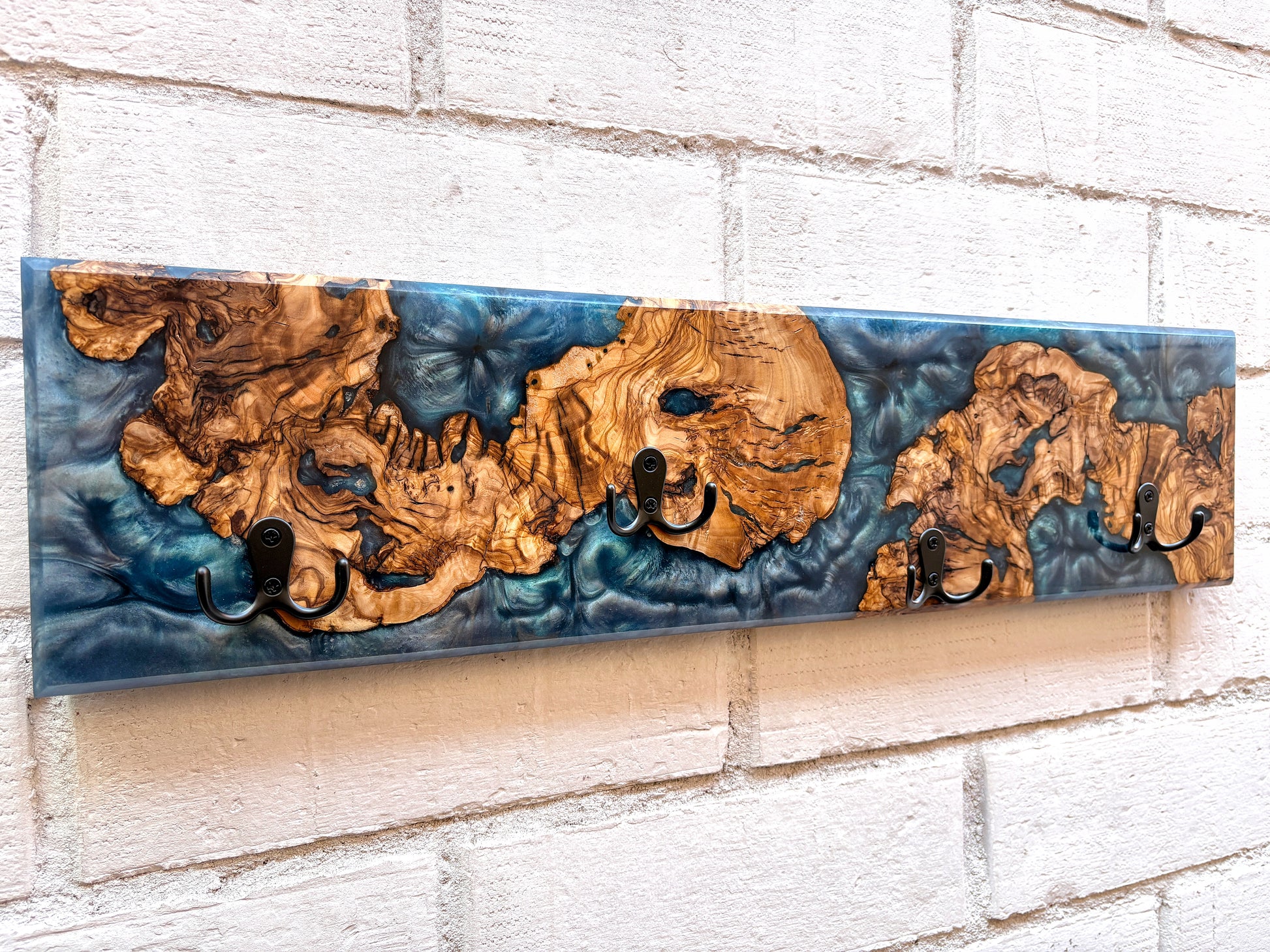 Perchero de madera de olivo con resina epoxy azul, detalle de vetas naturales