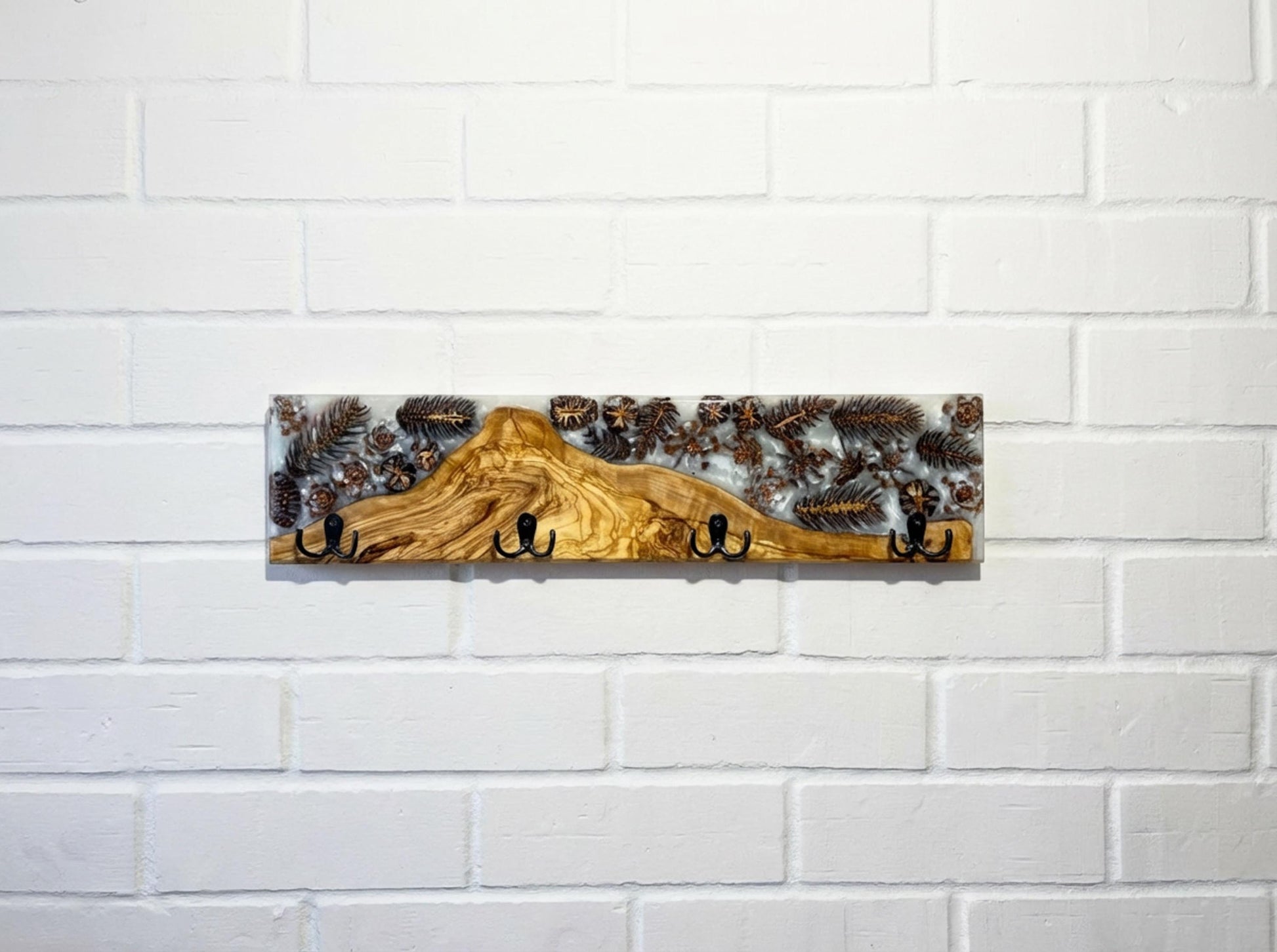 Perchero de pared en madera de olivo con resina epoxy y piñas naturales, diseño artesanal