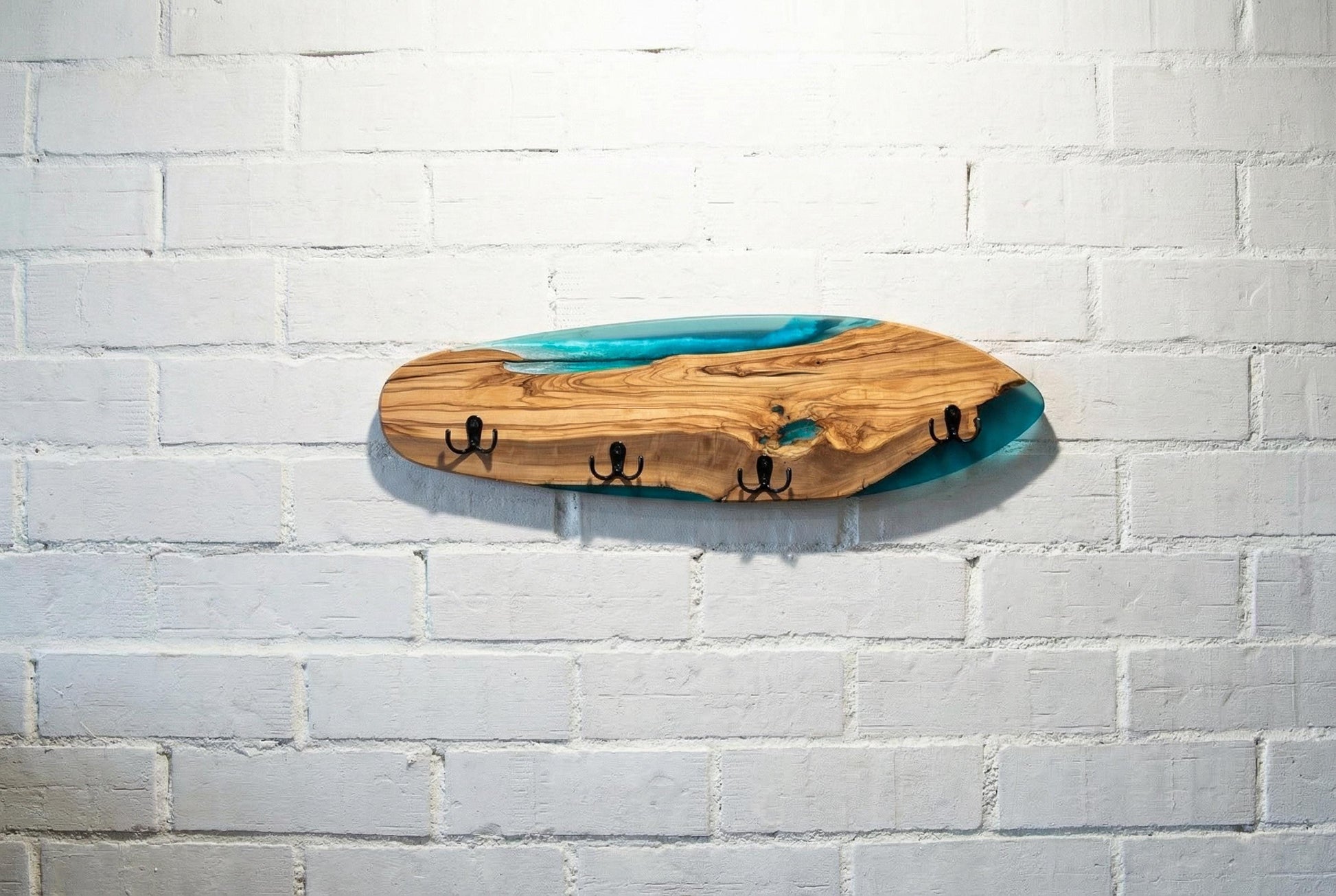 Perchero de pared en forma de skate en madera de olivo con resina epoxy azul turquesa