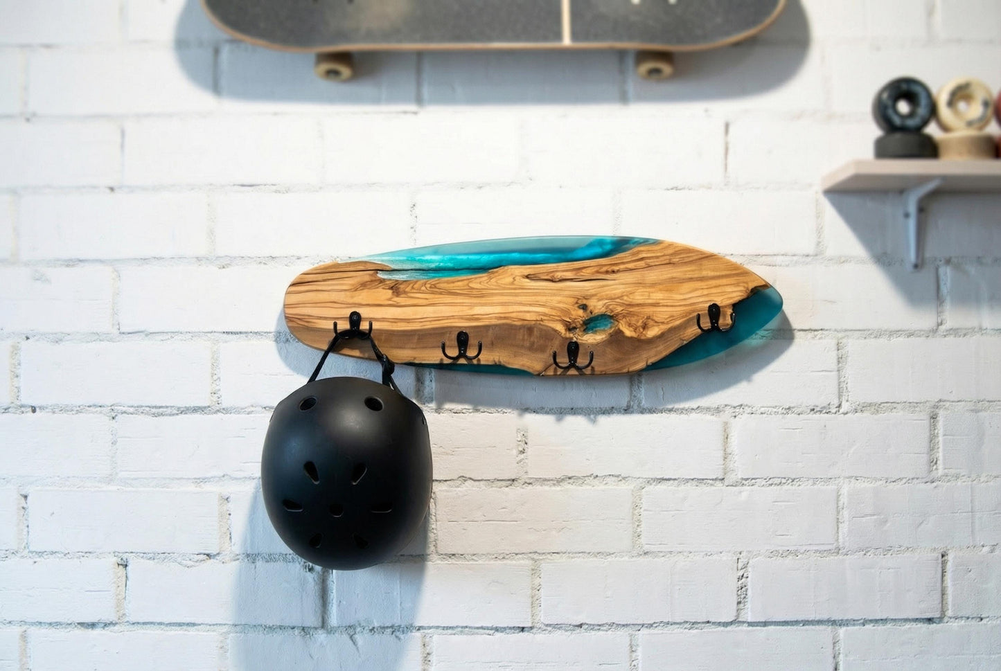Perchero skate artesanal de olivo con resina epoxy azul en uso con casco