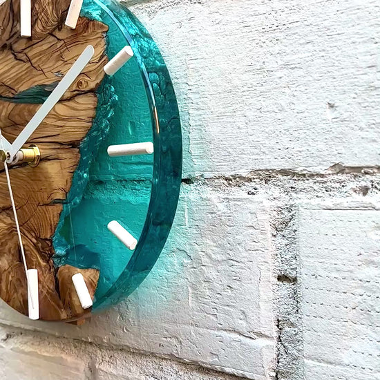 Video de reloj artesanal de madera de olivo con resina epoxy turquesa instalado en pared
