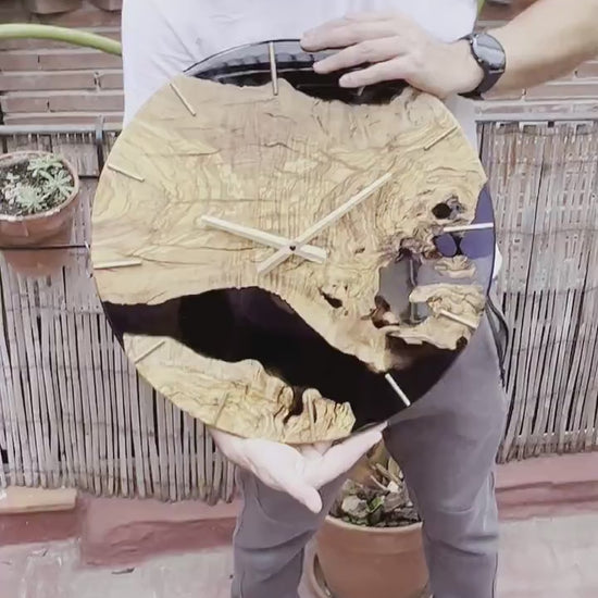 Video de artesano presentando reloj de madera de olivo con resina epoxy negra