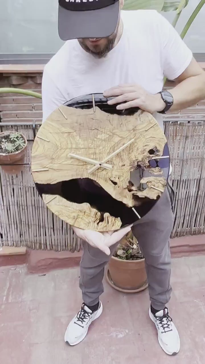 Video de artesano presentando reloj de madera de olivo con resina epoxy negra