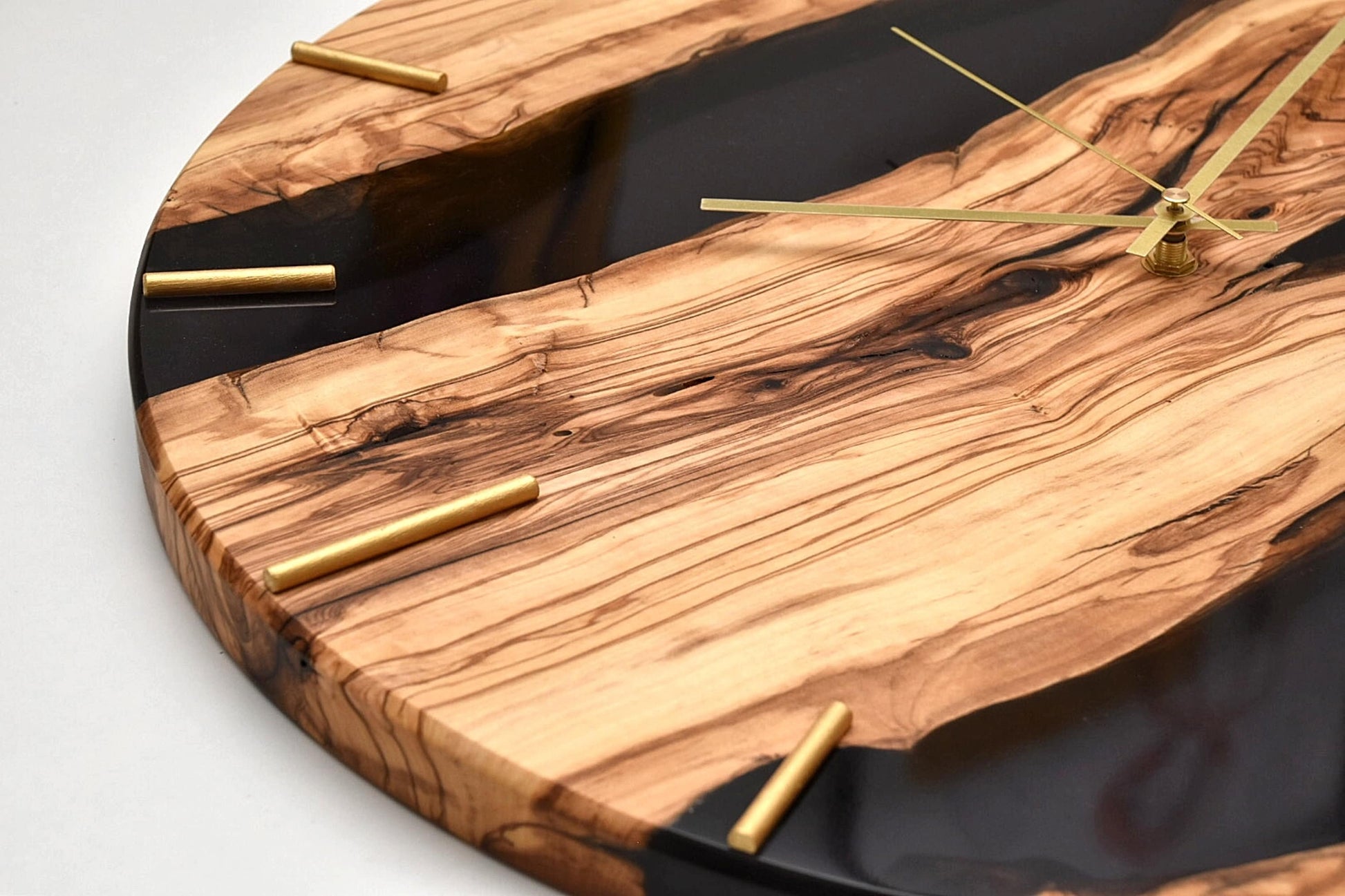 Reloj de madera de olivo con resina epoxi visto desde arriba, acabado artesanal.