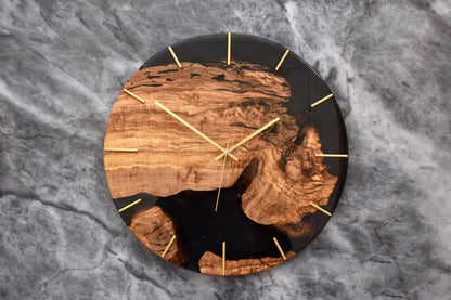 Reloj redondo de madera de olivo con diseño moderno y detalles en dorado.