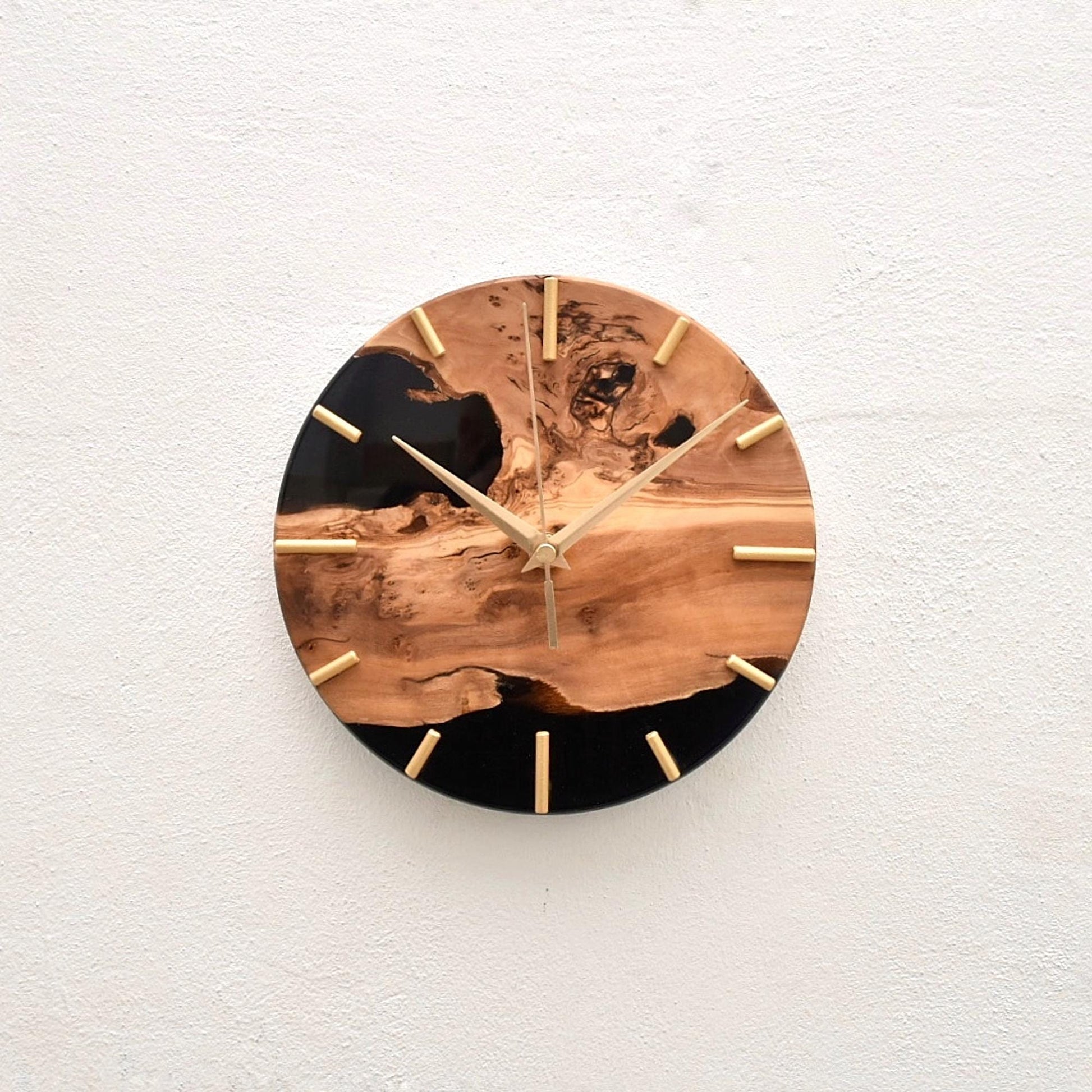 Reloj de madera de olivo sobre pared clara en estilo minimalista.