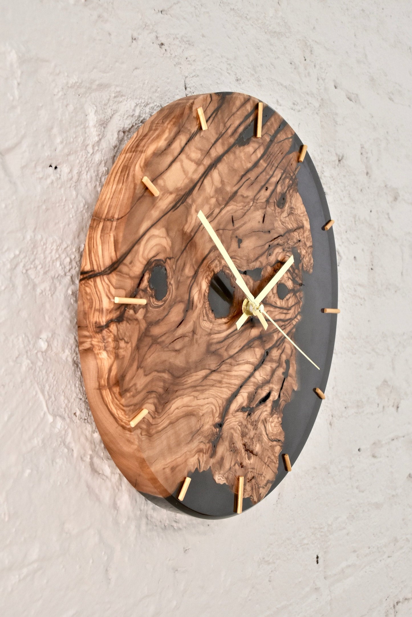 Reloj de pared artesanal en madera de olivo con vetas naturales y resina epoxi.