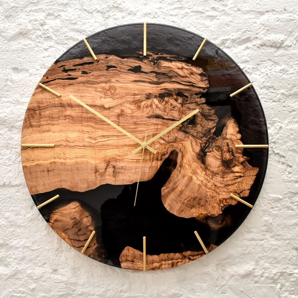 Reloj artesanal de madera de olivo con vetas naturales y resina oscura.