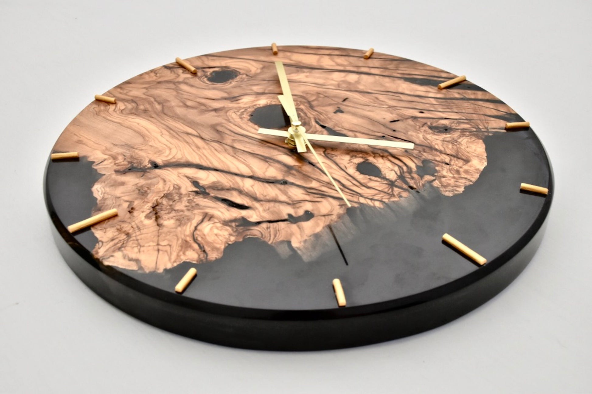 Reloj de madera de olivo con resina epoxi visto desde arriba, acabado artesanal.