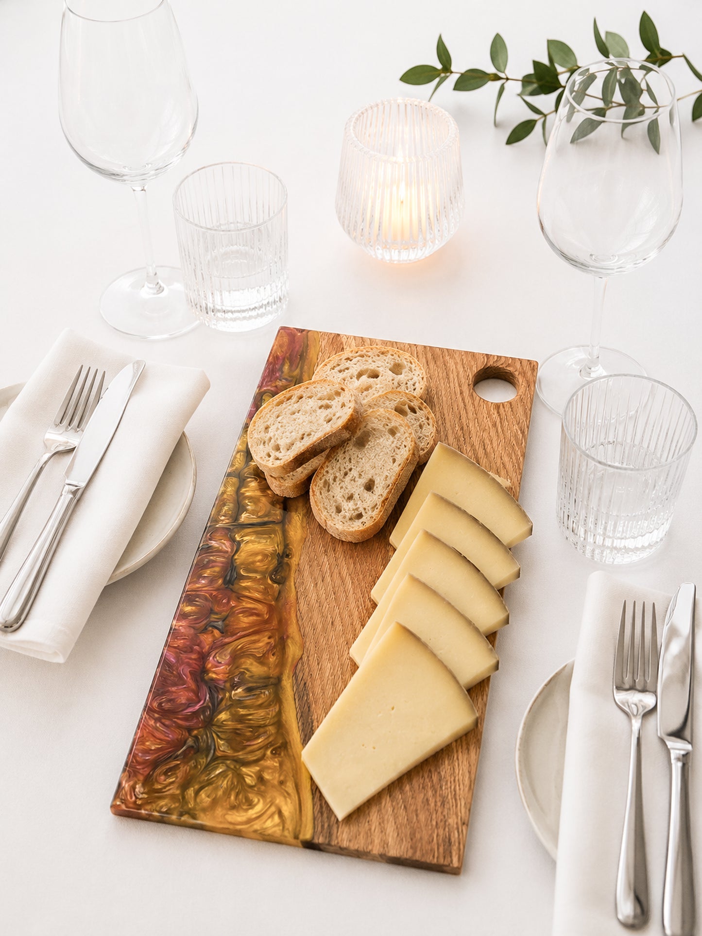 Tabla de servir de roble macizo y resina epoxi presentada en mesa elegante con queso y pan.