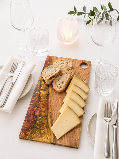 Tabla de servir de roble macizo y resina epoxi presentada en mesa elegante con queso y pan.